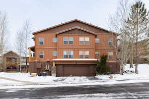 View of front of home with a garage and central AC