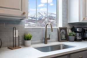 Room details with a mountain view, sink, tasteful backsplash, and light stone countertops