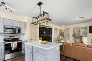 Kitchen with appliances with stainless steel finishes, dark hardwood / wood-style floors, tasteful backsplash, a kitchen island, and hanging light fixtures