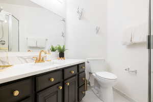 Bathroom featuring tile patterned flooring, vanity, walk in shower, and toilet