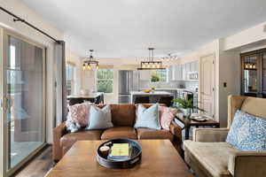 Living room featuring rail lighting, a textured ceiling, dark wood-type flooring, and a chandelier