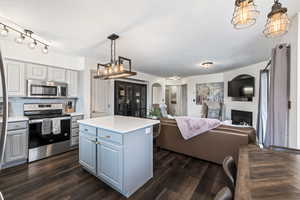 Kitchen with decorative light fixtures, rail lighting, dark hardwood / wood-style floors, a kitchen island, and stainless steel appliances