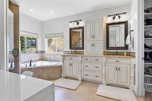 Bathroom featuring tiled tub, vanity, and tile patterned floors