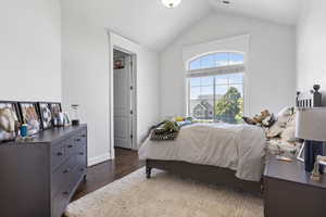 Bedroom featuring dark wood-type flooring and vaulted ceiling