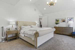 Carpeted bedroom with high vaulted ceiling and a notable chandelier