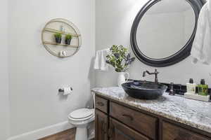 Bathroom with hardwood / wood-style floors, toilet, and vanity