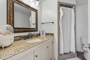 Bathroom with a shower with shower curtain, backsplash, vanity, and toilet