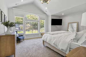 Carpeted bedroom with multiple windows and vaulted ceiling