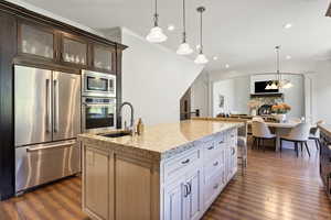 Kitchen featuring white cabinetry, ornamental molding, an island with sink, dark wood-type flooring, and built in appliances