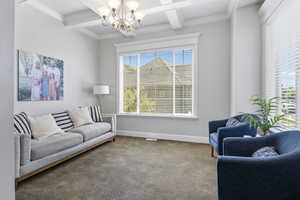 Interior space featuring carpet flooring, a healthy amount of sunlight, beamed ceiling, and a chandelier