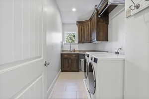 Laundry area with sink, cabinets, independent washer and dryer, and light tile patterned floors