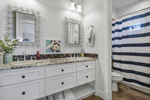 Bathroom with toilet, vanity, a shower with curtain, and tile patterned floors