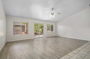 Spare room with a wealth of natural light, light wood-type flooring, vaulted ceiling, and ceiling fan