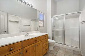 Bathroom featuring tile patterned floors, toilet, an enclosed shower, and vanity