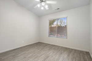 Spare room featuring light wood-type flooring, vaulted ceiling, and ceiling fan