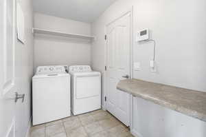 Clothes washing area with washing machine and dryer and light tile patterned floors