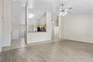 Unfurnished living room featuring light hardwood / wood-style flooring, ceiling fan, and high vaulted ceiling