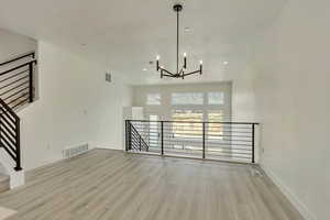 Unfurnished dining area with light hardwood / wood-style floors and a chandelier