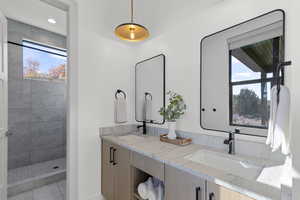 Full bath with double vanity and tiled shower