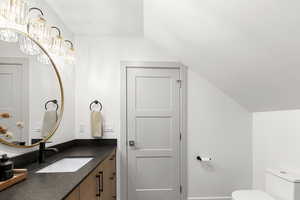 Bathroom featuring vanity, a chandelier, and lofted ceiling