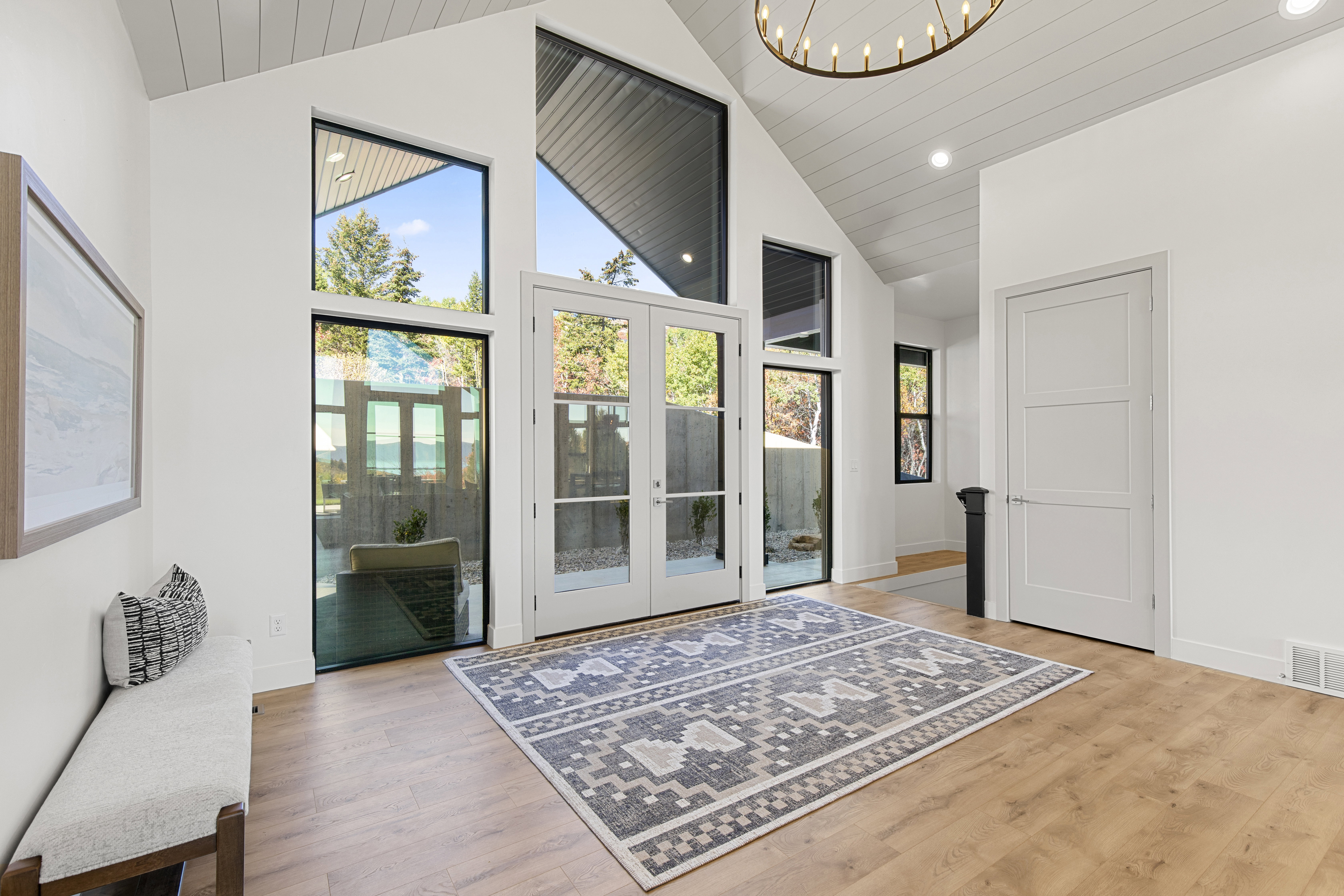 Doorway featuring french doors, high vaulted ceiling, wood finished floors, recessed lighting, and a chandelier