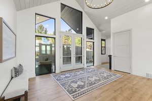 Doorway featuring french doors, high vaulted ceiling, wood finished floors, recessed lighting, and a chandelier