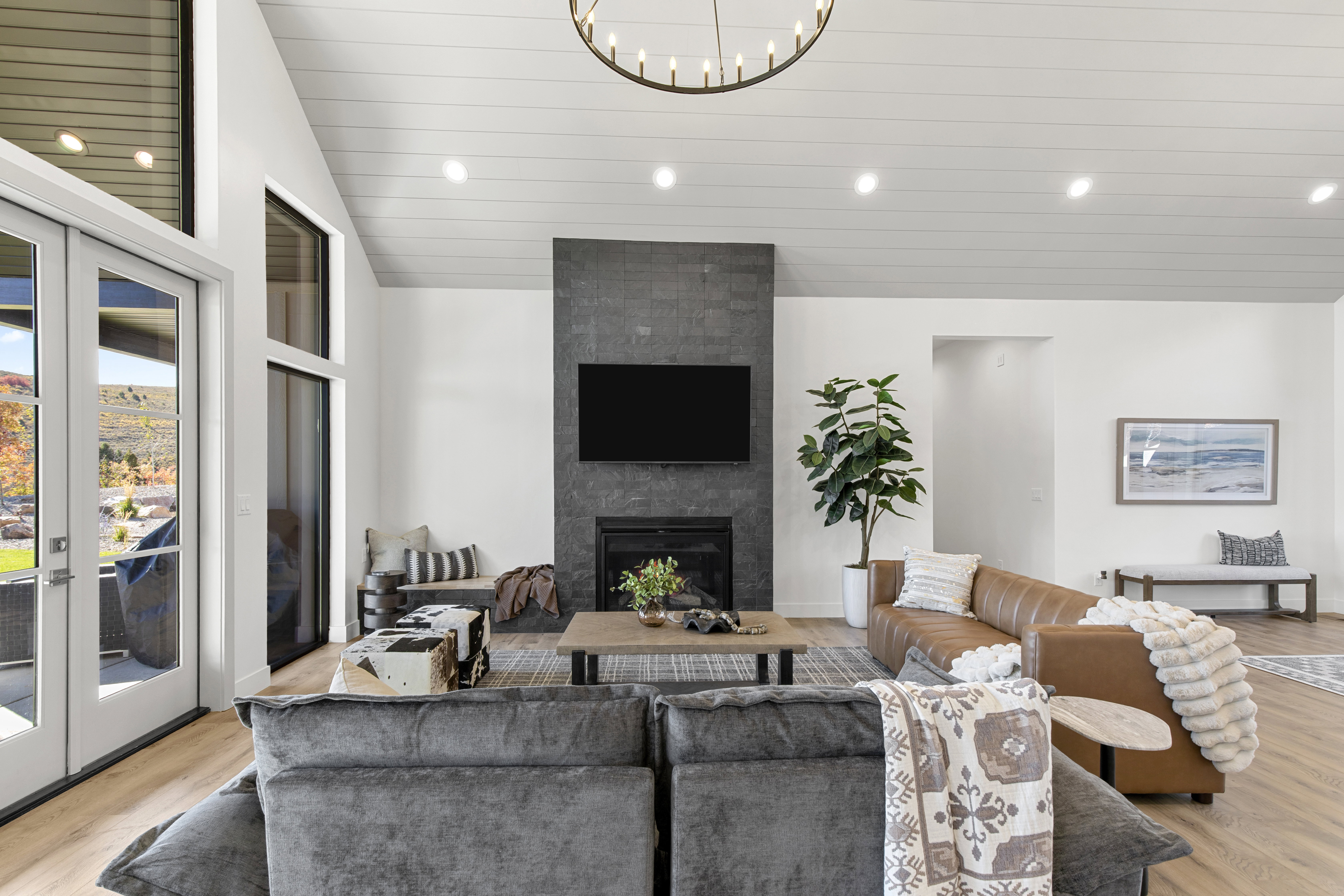 Living area with light wood finished floors, recessed lighting, lofted ceiling, a large fireplace, and french doors