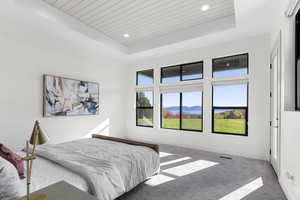 Carpeted bedroom with a tray ceiling, a mountain view, wood ceiling, and recessed lighting