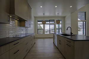 Kitchen with sink, decorative light fixtures, light brown cabinets, an island with sink, and black electric stovetop