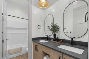 Bathroom featuring light wood-style floors, double vanity, and shower / bath combination with curtain