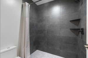 Bathroom featuring a shower stall and toilet