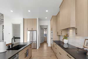 Kitchen featuring light brown cabinets, appliances with stainless steel finishes, light wood-style floors, recessed lighting, and decorative backsplash