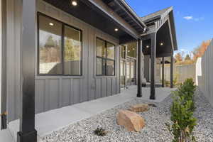 View of side of home featuring board and batten siding, a fenced backyard, and a patio area