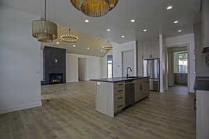 Kitchen with sink, decorative light fixtures, appliances with stainless steel finishes, an island with sink, and hardwood / wood-style floors