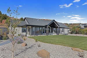 Rear view of house with a patio area, a yard, roof with shingles, and board and batten siding