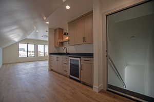 2nd kitchen in ADU with lofted ceiling, light brown cabinetry, sink, and light wood-type flooring