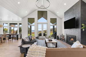 Living area featuring light wood-type flooring, a fireplace, a chandelier, recessed lighting, and high vaulted ceiling