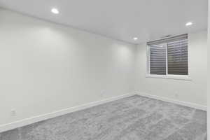 Carpeted empty room with baseboards and recessed lighting