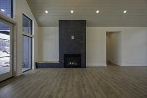Unfurnished living room with a large fireplace, hardwood / wood-style floors, and high vaulted ceiling