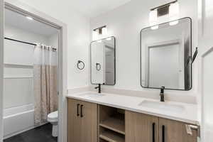 Full bath with shower / bath combo, double vanity, and dark tile patterned flooring