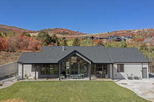 Back of property with a patio, a mountain view, a shingled roof, and a lawn