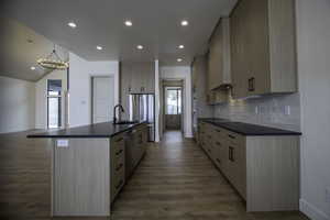 Kitchen with sink, stainless steel appliances, tasteful backsplash, a center island with sink, and light brown cabinets