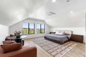 Bedroom with lofted ceiling and light wood finished floors