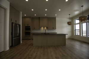 Kitchen featuring premium range hood, decorative backsplash, hanging light fixtures, stainless steel appliances, and light brown cabinets