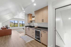 Indoor wet bar with light brown cabinetry, open shelves, recessed lighting, wine cooler, and light wood-style flooring