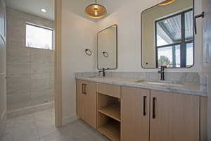 Bathroom featuring tile patterned flooring, vanity, a healthy amount of sunlight, and tiled shower