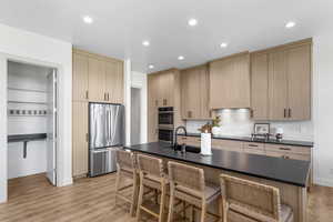Kitchen with light brown cabinets, stainless steel appliances, light wood-type flooring, and recessed lighting