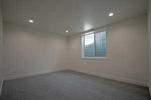 Empty room featuring dark colored carpet