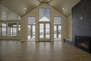 Unfurnished living room featuring high vaulted ceiling, a fireplace, wood-type flooring, wooden ceiling, and french doors