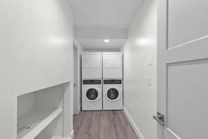 Laundry area featuring dark wood-style flooring, stacked washing machine and dryer, and recessed lighting